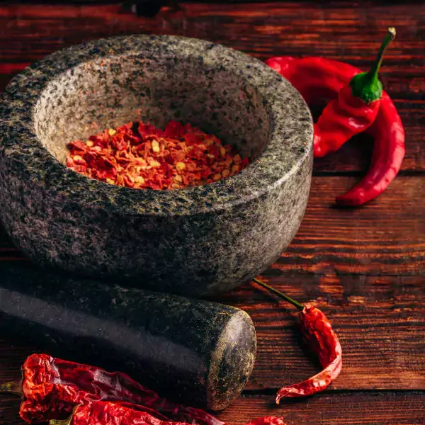 Crushed chile pepper flakes in mortar and pestle bowl.